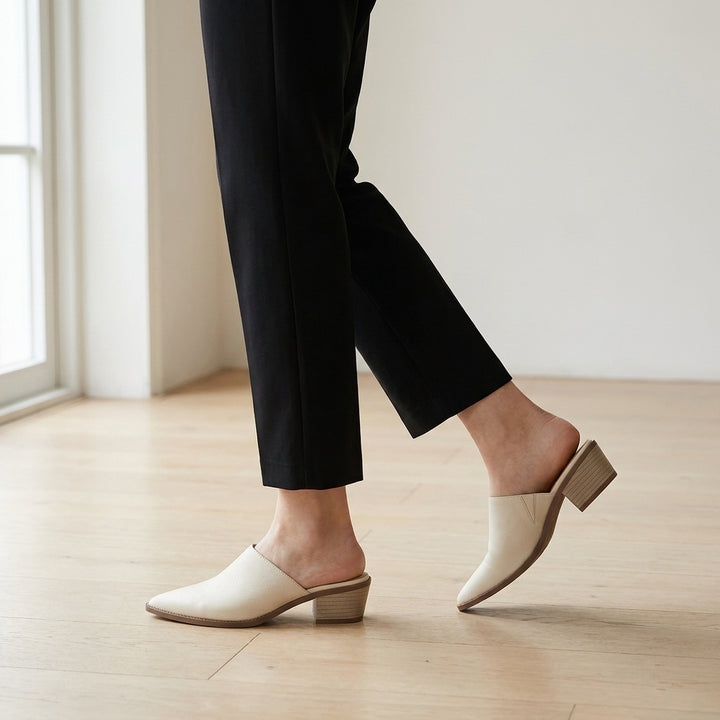 Lucera Leather Mules — Cream, worn mid-stride in a gallery interior