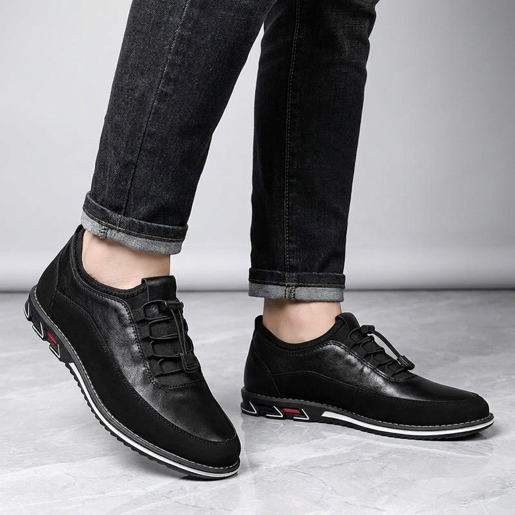 Anagni No-Tie Dress Shoes — Black, worn with dark cuffed jeans, knee-down view on light-grey marble