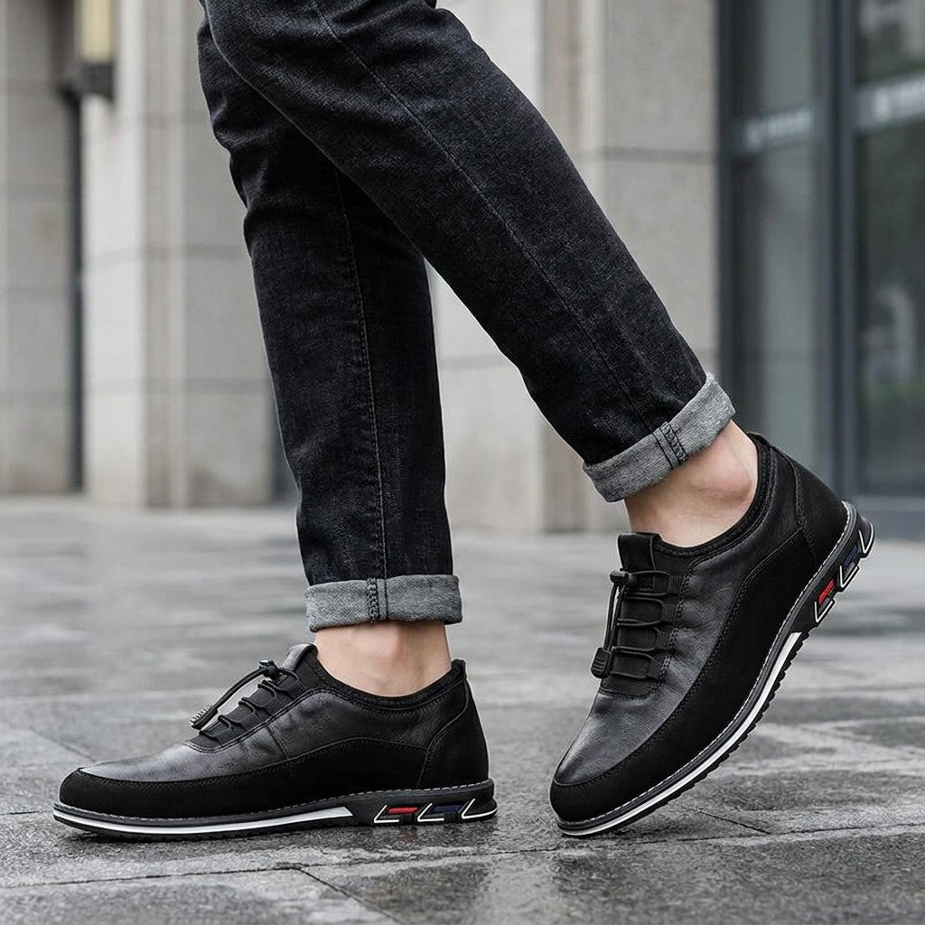 Anagni No-Tie Dress Shoes — Black, worn with dark cuffed jeans on a city sidewalk outside an office building