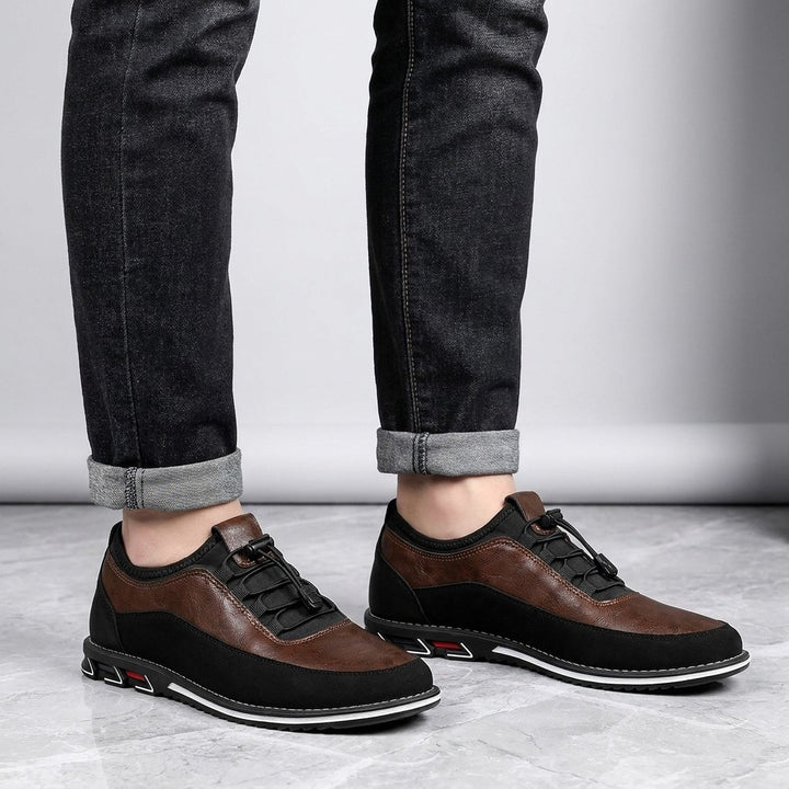 Anagni No-Tie Dress Shoes — Chestnut Brown, worn with dark cuffed jeans, knee-down view on light-grey marble