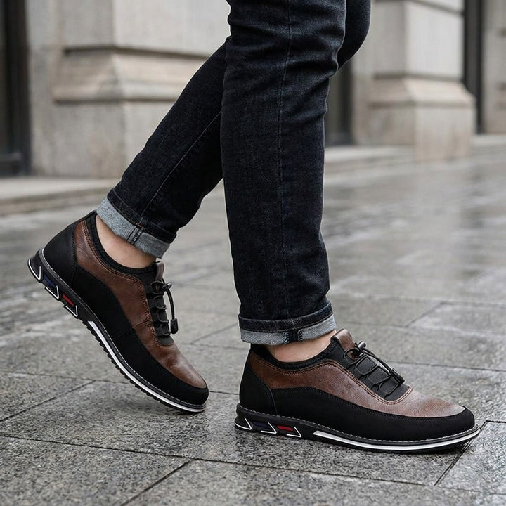 Anagni No-Tie Dress Shoes — Chestnut Brown, worn with dark cuffed jeans on a city sidewalk outside an office building