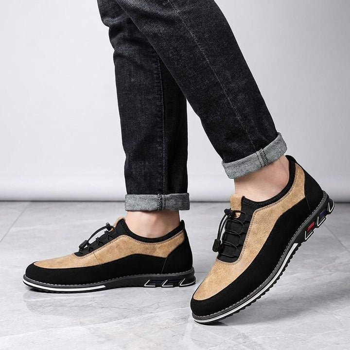 Anagni No-Tie Dress Shoes — Sand, worn with dark cuffed jeans, knee-down view on light-grey marble