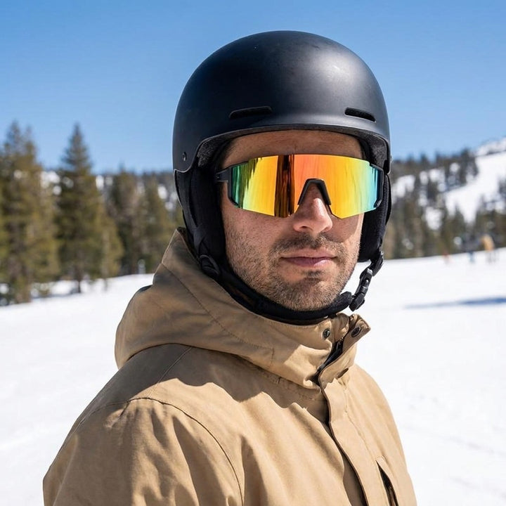 Tellaro Shield Sunglasses — Black / Fire Mirror, worn by a man in a helmet snowboarding sunny spring snow at Mammoth