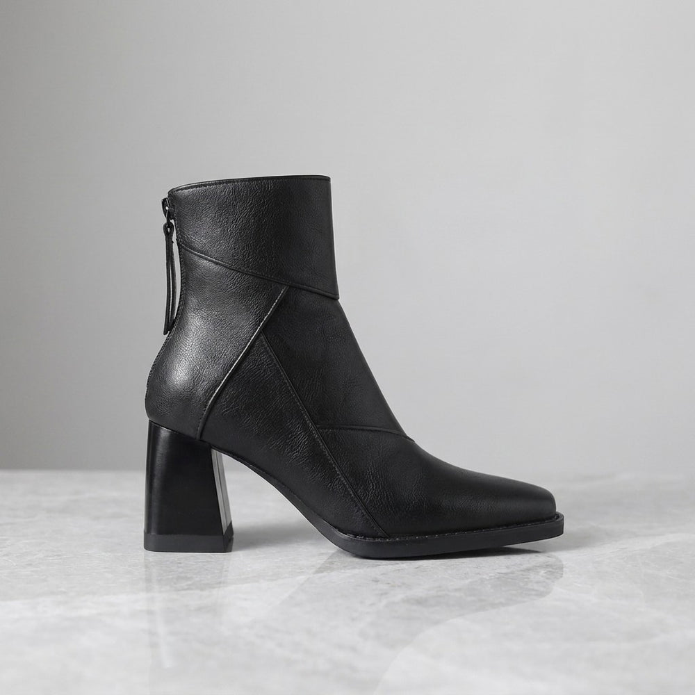 Bormio Paneled Ankle Boots — Black, single boot in side profile on light grey marble
