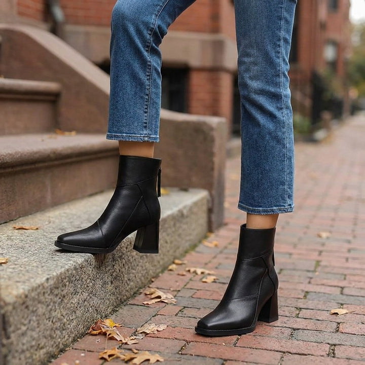 Bormio Paneled Ankle Boots — Black, worn with cropped blue jeans on a brick sidewalk by brownstone steps