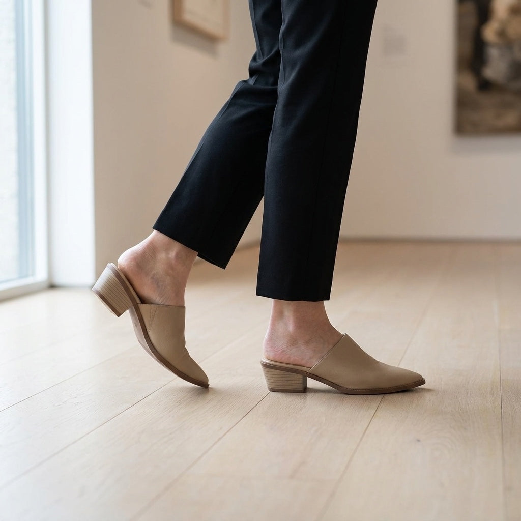Lucera Leather Mules — Sand, worn mid-stride in a gallery interior
