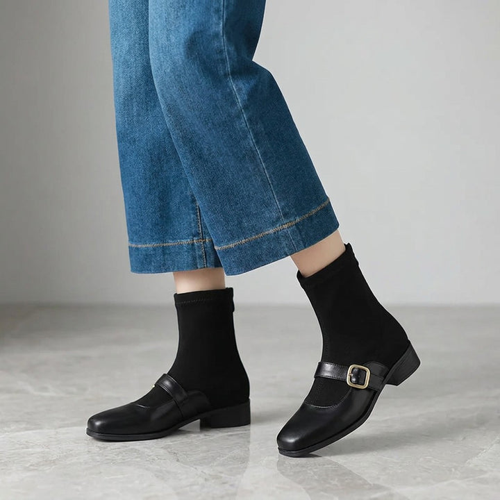 Cosenza Square Toe Ankle Boots — Black, worn by a woman, knee down, on grey marble