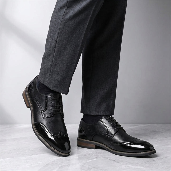Tortona Leather Wingtip Brogues — Black, worn with suit trousers on a marble floor