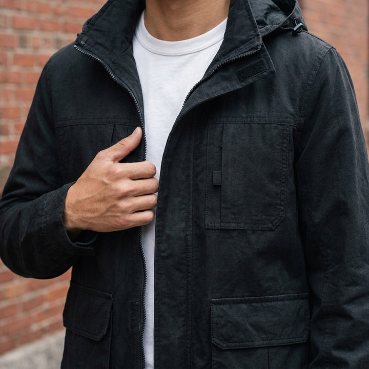 Close-up of the Faenza Hooded Cargo Jacket in Black worn over a white tee, showing the stand collar, hood and velcro chest pockets