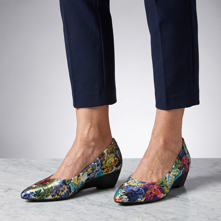 Maiori Pointed-Toe Pumps — Teal Floral, worn by a woman in navy cropped trousers, knee down, on marble