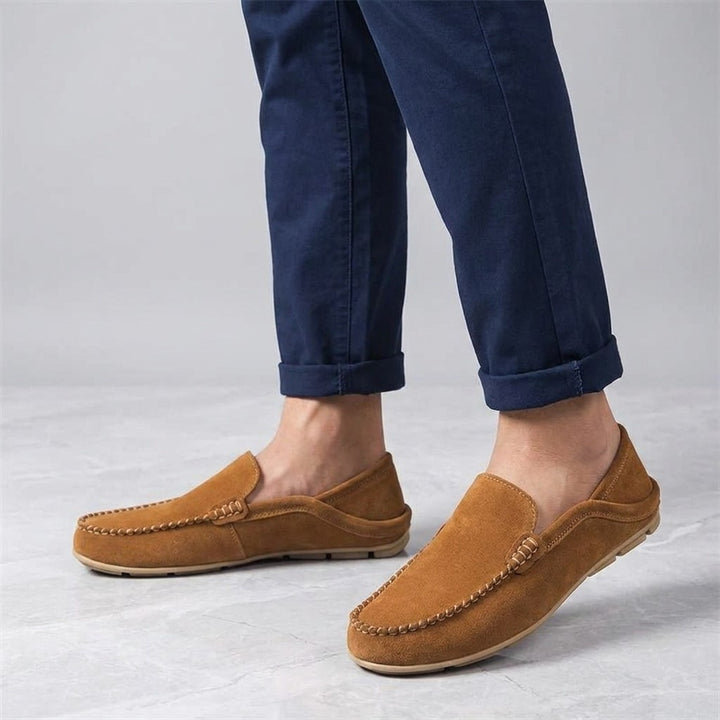 Varazze Suede Loafers — Apricot, worn sockless with cuffed navy chinos, knee-down on light grey marble