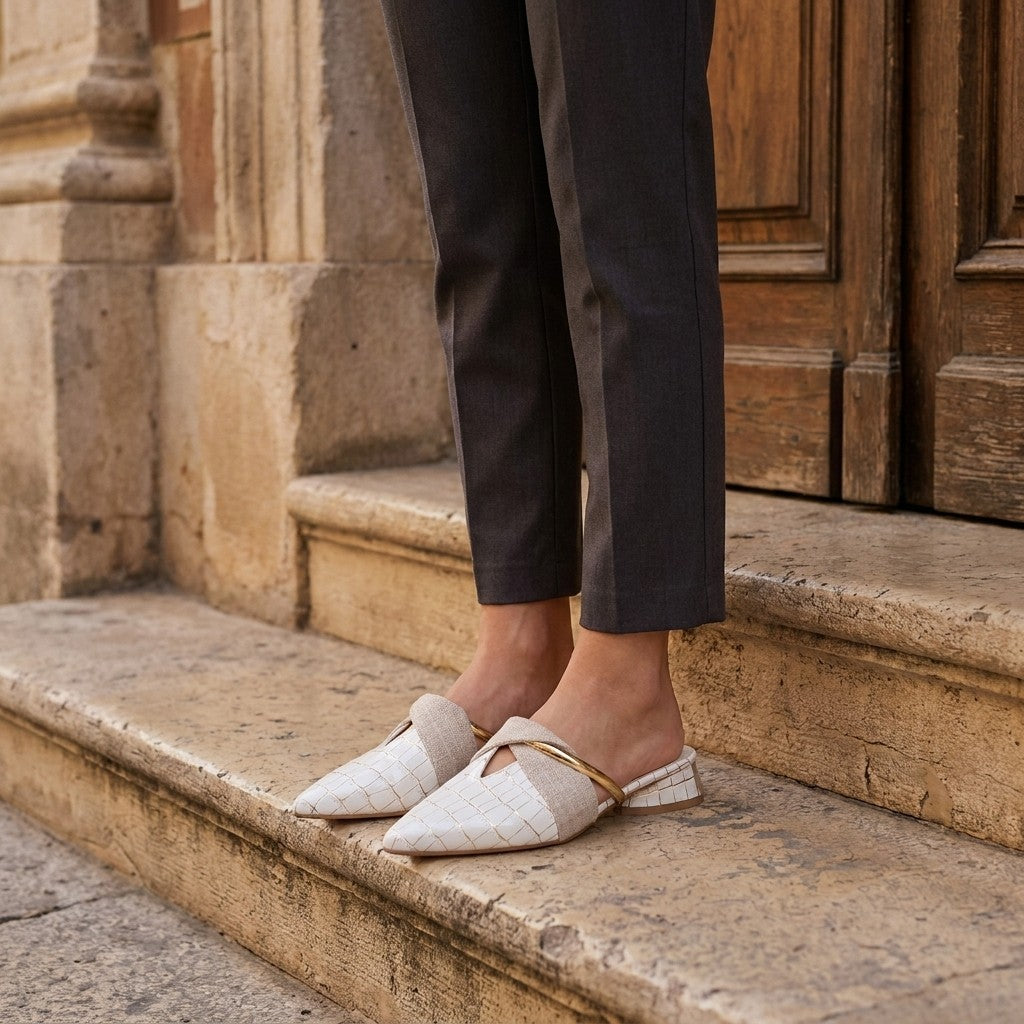 Tivoli Croc-Embossed Mules — White, on model at restaurant steps