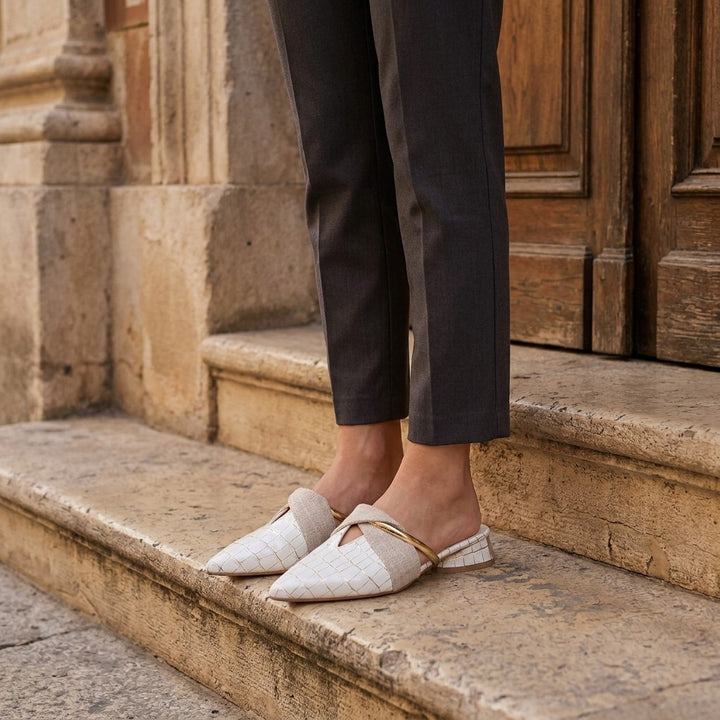 Tivoli Croc-Embossed Mules — White, on model at restaurant steps